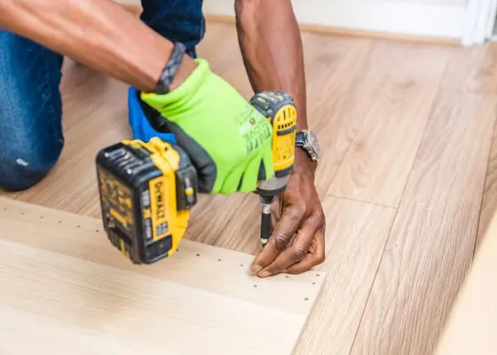 Skilled handyman installing hardwood flooring in a living room